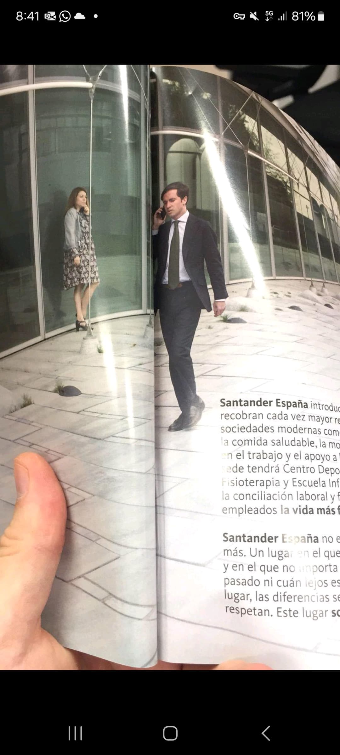 Hombre con traje caminando y hablando por teléfono frente a un edificio de oficinas moderno.